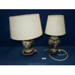 Two table lamps with cream shades and ginger jar shape bases on wooden plinths,