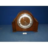 A wooden anvil mantle clock with Arabic numerals and pendulum, no key.