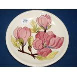 A Moorcroft cream ground Magnolia plate, 10" diameter, WM initials to rear, some crazing.