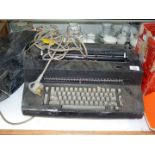 An IBM electric typewriter and cover with box of ribbons and tape.