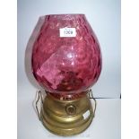 A Church oil heater lamp with brass base, chimney and cranberry globe, 16'' tall.
