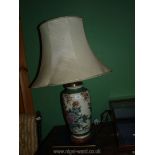 A Chinese lamp in gilded flower pattern with a wooden base and white shade.
