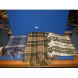Three woolen throws with fringed edges; blue, green/orange and green/cream. Single sizes.