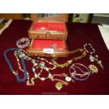 A quantity of costume jewellery in a wooden box containing necklaces, bracelets, etc.