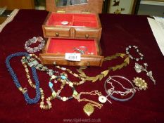 A quantity of costume jewellery in a wooden box containing necklaces, bracelets, etc.