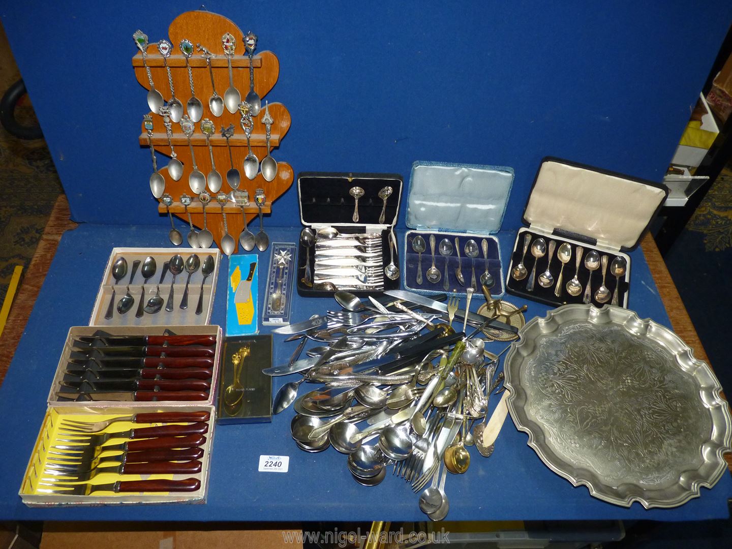 A quantity of mixed cutlery including a rack of souvenir spoons, boxed sets of cake forks,
