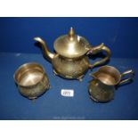 A well worn silver plated teapot, milk jug and sugar bowl having embossed decoration.
