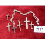 Six silver crosses of various sizes, one on a chain.