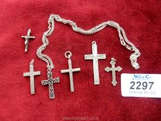 Six silver crosses of various sizes, one on a chain.