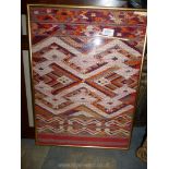 A framed piece of Thai Hill Tribe costume in geometric design in orange, white and reds,