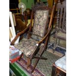 An arts and crafts style Campaign folding Mahogany framed Armchair having dark green ground fabric