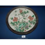 An oriental charger with a dark brown border decorated with a bird and floral scene to the centre,