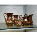 Three Old Court graduated lustre jugs with painted flowers, a Wade lustre jug and one other.