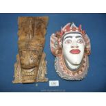 Two wooden wall hanging head masks, one having been painted.