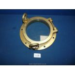 A Brass Porthole with loop screw-down fasteners, 9" diameter.