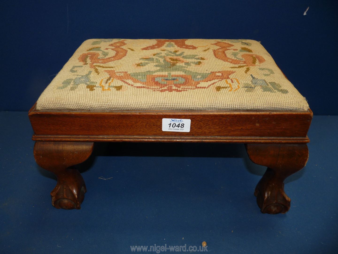 A tapestry topped Footstool with ball and claw feet, some wear, 10'' x 11'' x 8 1/4''.