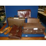Three vintage suitcases with a leather briefcase and a pair of wooden shoe lasts.
