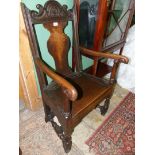 An early dark Oak framed Commode Armchair standing on turned legs and stretchers and with scroll