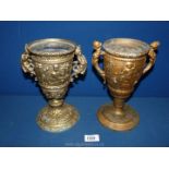 Two metal Urns in gilt colour finish, one with cherub handles, the other with lady handles,