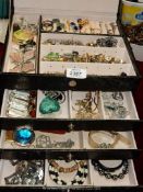 A black jewellery box containing; earrings, bracelets, cufflinks, gold coloured necklaces,