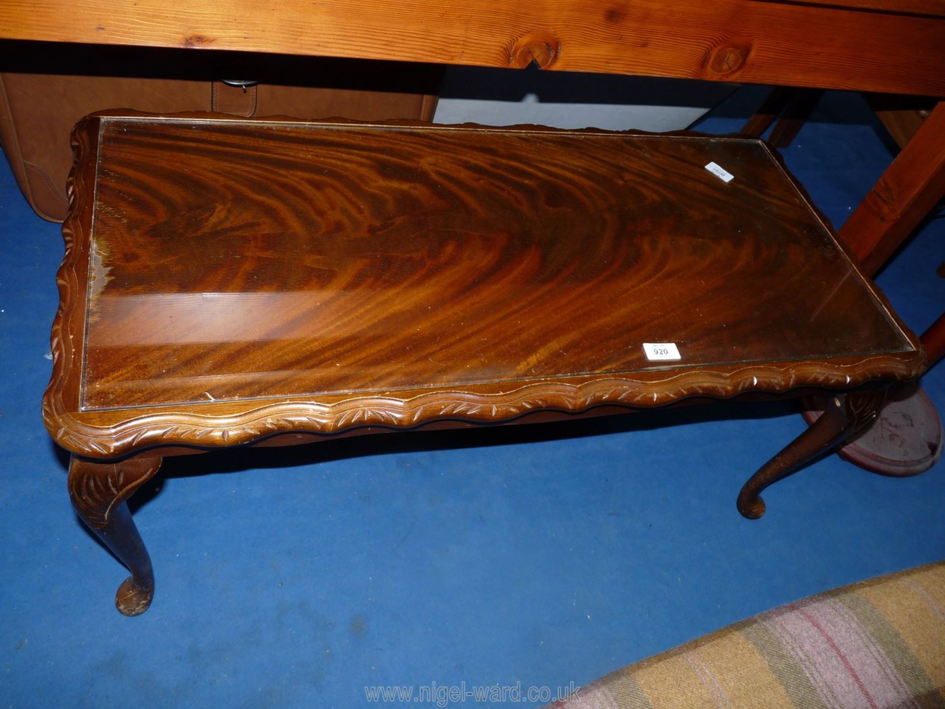 A darkwood coffee table with shaped edge and glass top insert,