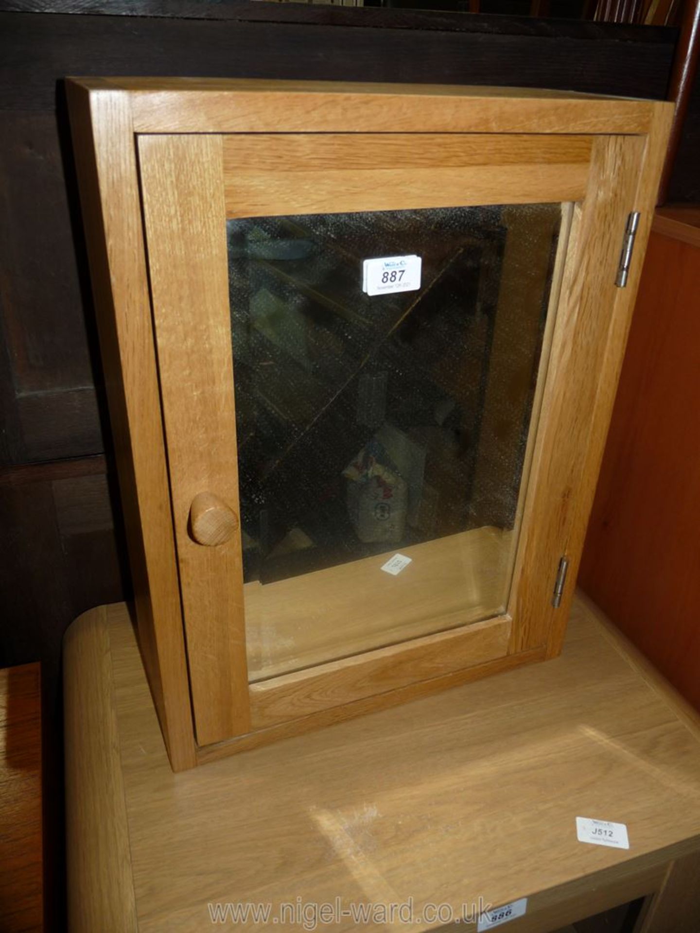 A light oak effect bathroom cabinet with mirrored door.