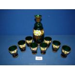 A green and gilt decanter (no stopper) set having eight shot glasses.