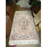 A fringed, pink and mauve floral panelled rug, 67'' x 36''.