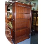 A dark Oak floor standing full height bookcase having carved upper frieze,