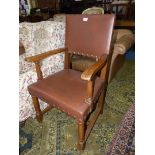 An Oak framed open-armed Elbow Chair on turned front legs and with an 'H' stretcher and brass