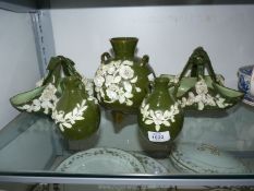 Five pieces of dark green porcelain with applied cream floral sprays: baskets and vases.