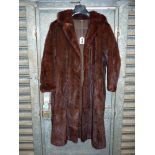 A long fur coat having 3/4 length sleeves, side slit pockets and in a red/brown colour, size M.