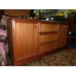 A contemporary Teak finished Sideboard with three central drawers flanked by opposing cupboard