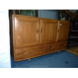 An Ercol Elm wood sideboard having three doors and a pair of drawers below,