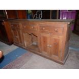 A pine Dog Kennel dresser base having three frieze drawers and a pair of double doored cupboards,