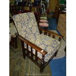 An oak framed semi- reclining Chair that converts to a bed with blue ground stylised floral and