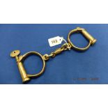 A of vintage handcuffs with original locking key,