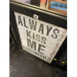 A framed sign 'Always Kiss Me'