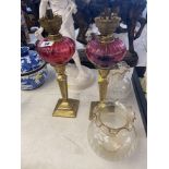 A pair of brass Peg lamps with Cranberry fonts and shades