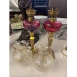 A pair of brass Peg lamps with Cranberry fonts and shades
