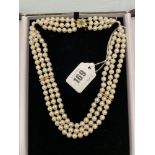 A three row cultured Pearl necklace on an 18ct Gold continental clasp set with Emeralds and