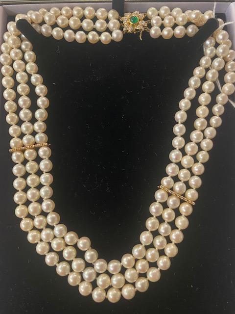 A three row cultured Pearl necklace on an 18ct Gold continental clasp set with Emeralds and