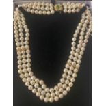 A three row cultured Pearl necklace on an 18ct Gold continental clasp set with Emeralds and