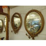 A pair of oval mirrors with sconces