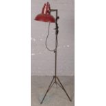 A metal industrial standard lamp with tripod base.