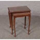 A carved hardwood nest of two tables with glass tops