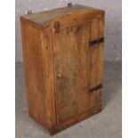 A wall mounted pine cupboard with metal hinges.