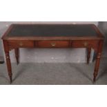 A mahogany leather top three drawer desk raised on turned supports. (78cm x 142cm)