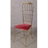 A brass Chiavari style chair, with red velvet upholstered seat.