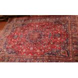 A large red ground full pile Iranian Kashan carpet with floral medallion design. (396cm x 288cm).